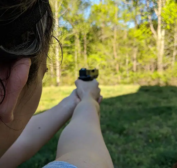 female shooter using three dot sight view over shoulder